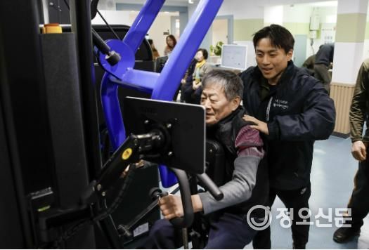 건강운동관리사가 어르신에게 근력운동 방법을 지도하고 있는 모습